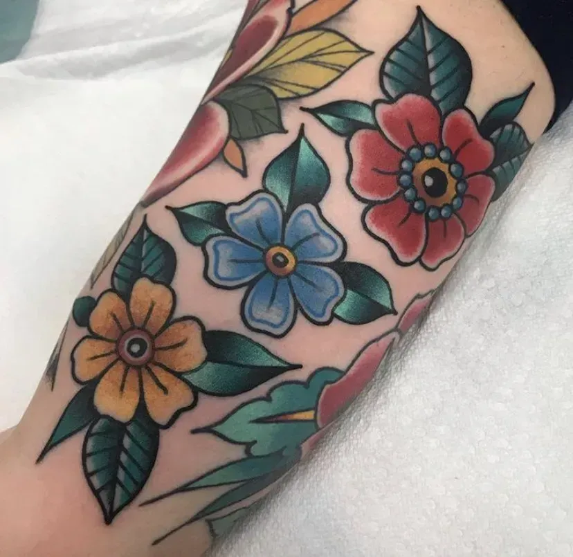 A tattoo of flowers and leaves on a person 's arm
