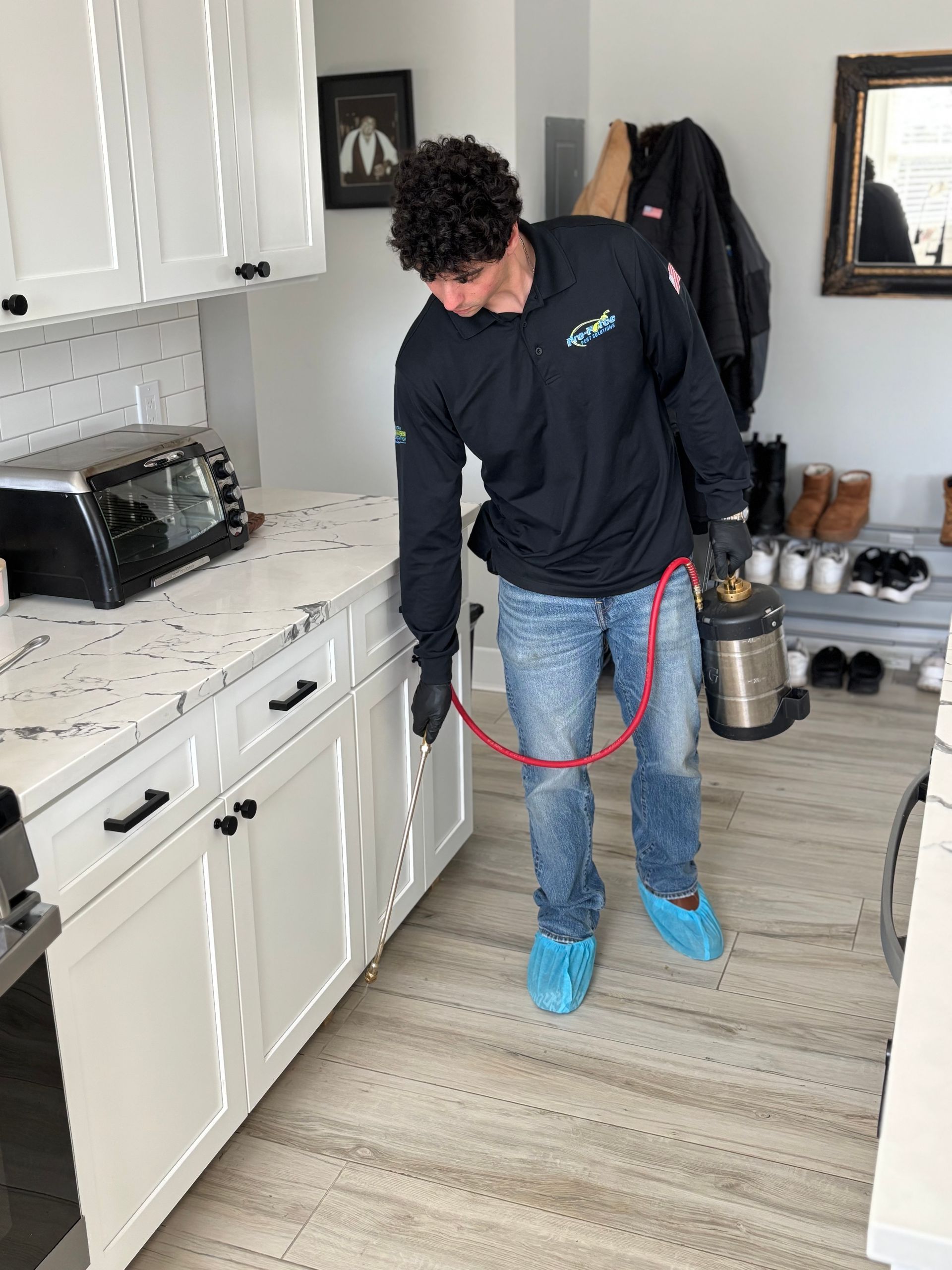 A man is spraying a kitchen with a hose.