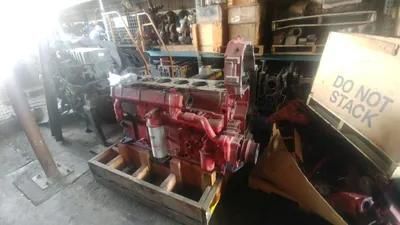 Red engine block on a wooden pallet, inside a cluttered workshop. 