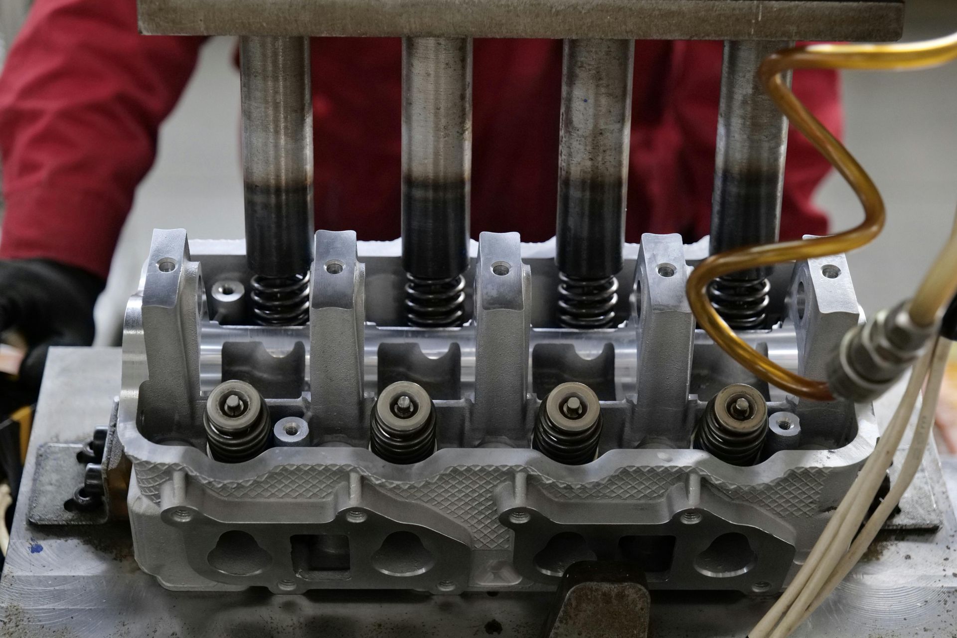 Engine cylinder head with four valve stems and springs, being worked on.