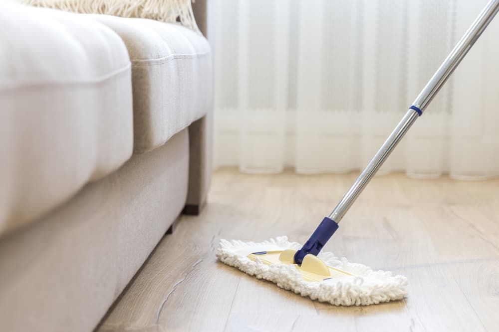 A Mop Is Being Used to Clean a Wooden Floor — Complete Clean Home Cleaning in Dapto, NSW