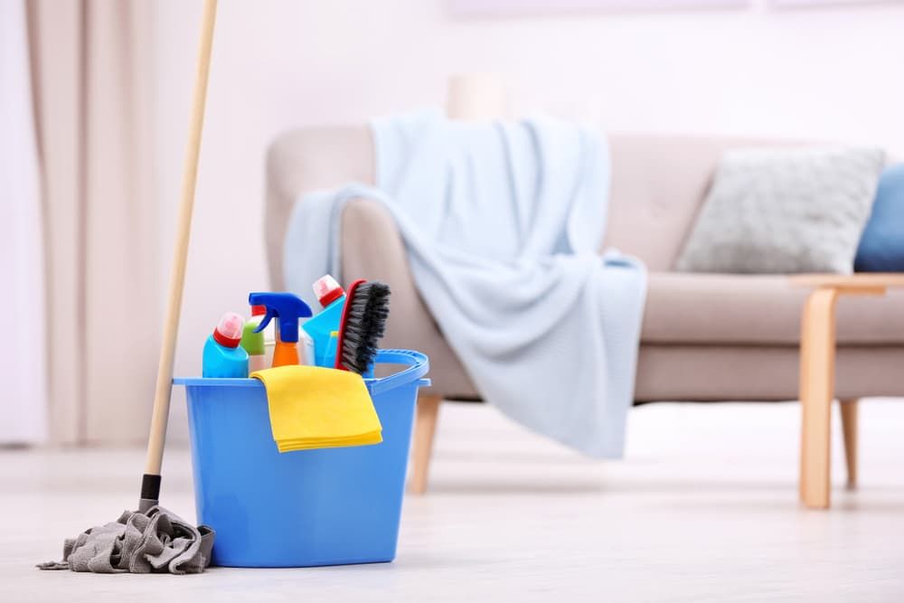 A Blue Bucket Filled with Cleaning Supplies and A Mop — Complete Clean Home Cleaning in Albion Park, NSW