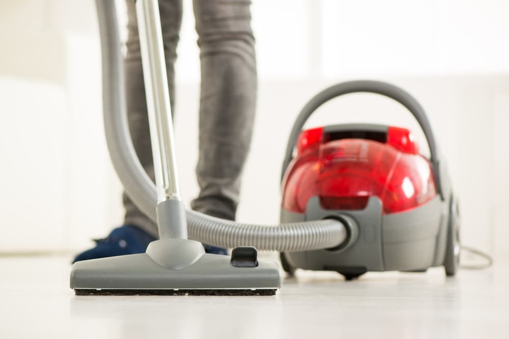 A Person Is Using a Vacuum Cleaner to Clean the Floor — Complete Clean Home Cleaning in Corrimal, NSW