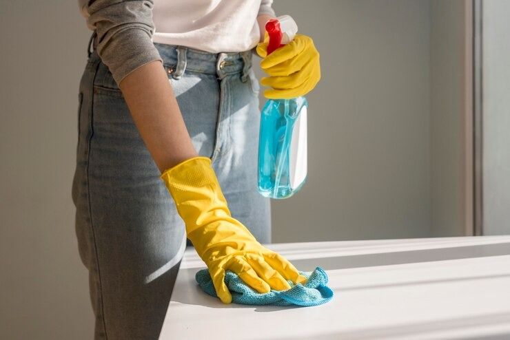 A Woman Wearing Yellow Gloves Is Cleaning a Counter — Complete Clean Home Cleaning in Corrimal, NSW