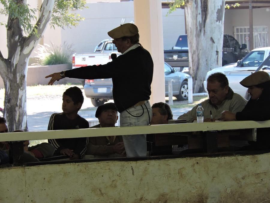 Un hombre con sombrero se encuentra frente a un grupo de personas.