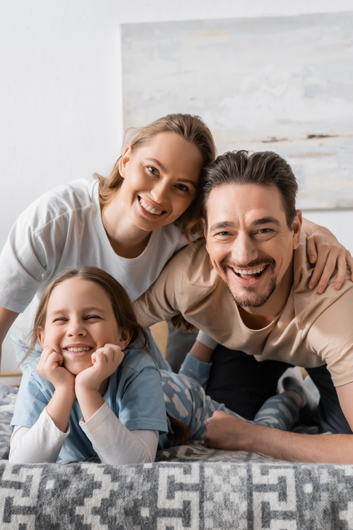 A family is sitting on the floor looking at a laptop computer.