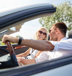 Family of three smiling in a car, sunlight.