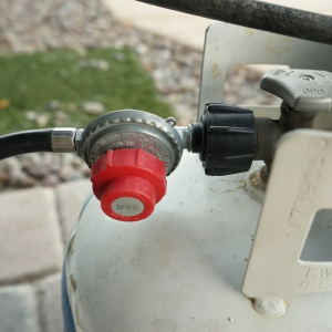 A close up of a propane tank with a red cap