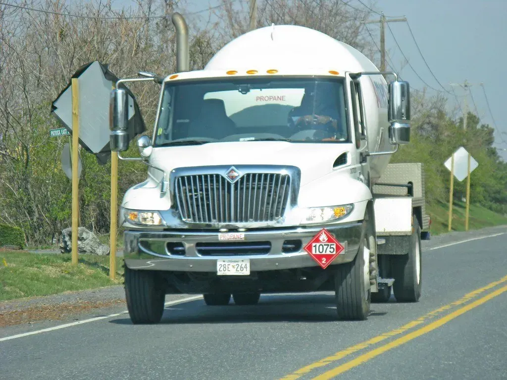 A white truck is driving down a road with a warning sign on the front