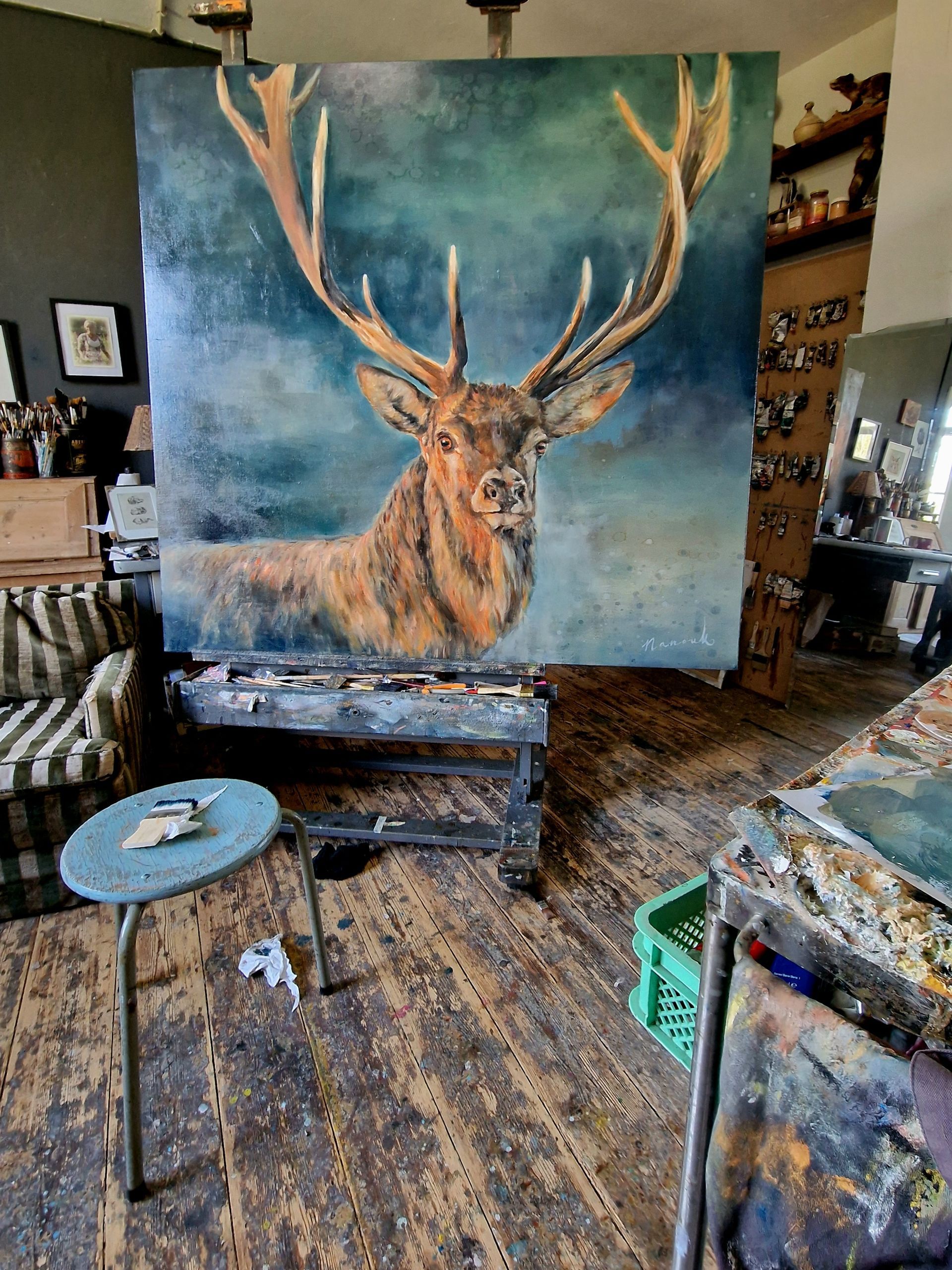 In een atelier wordt een groot schilderij van een hert geschilderd.