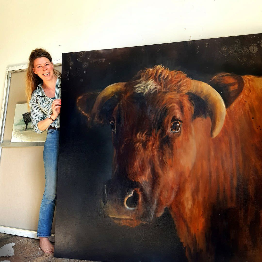 Een vrouw staat naast een groot schilderij van een stier