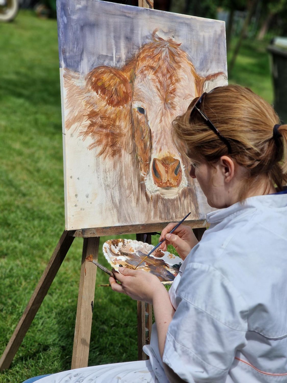 Een vrouw schildert een koe op een ezel.