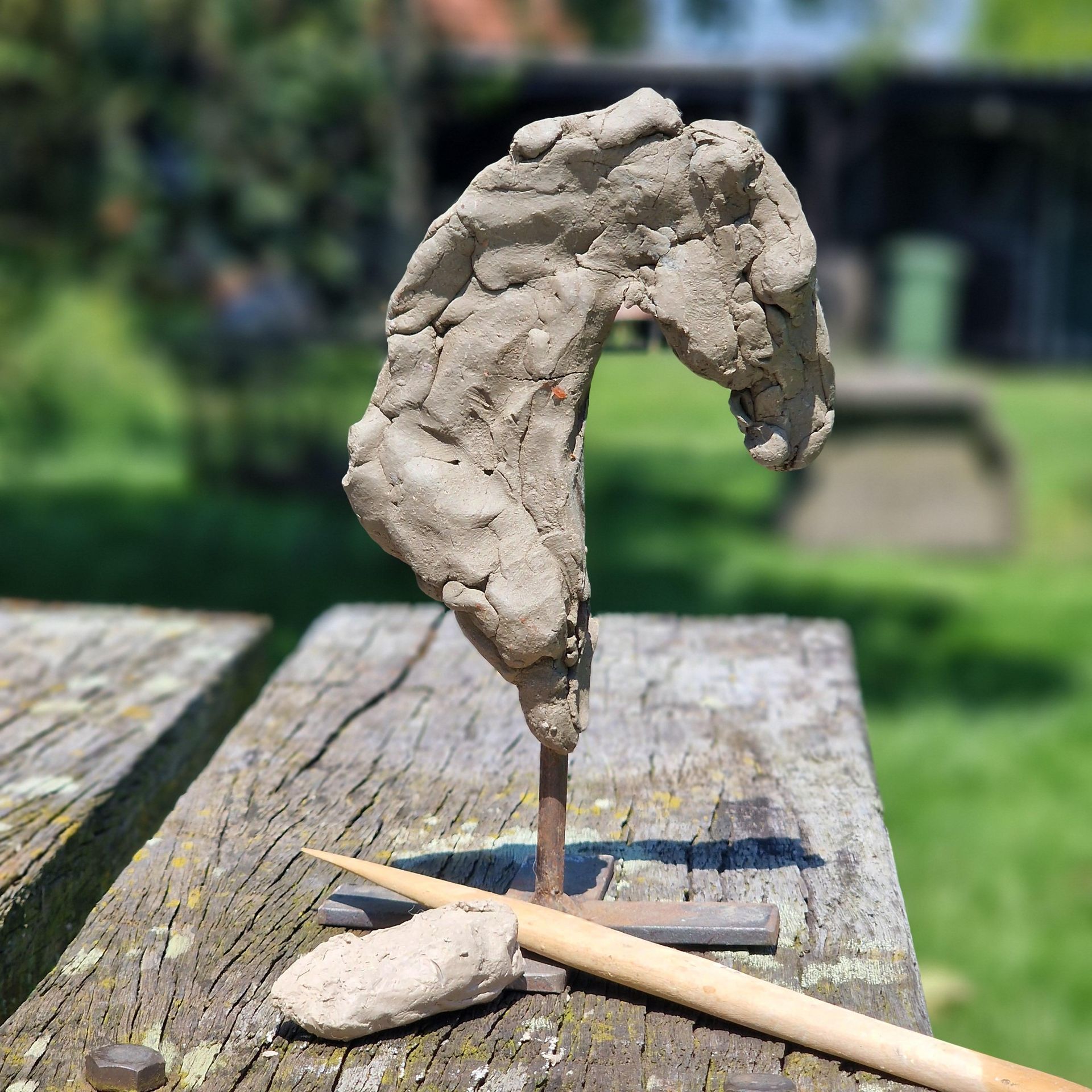 Een kleisculptuur van een paardenhoofd staat op een houten tafel.