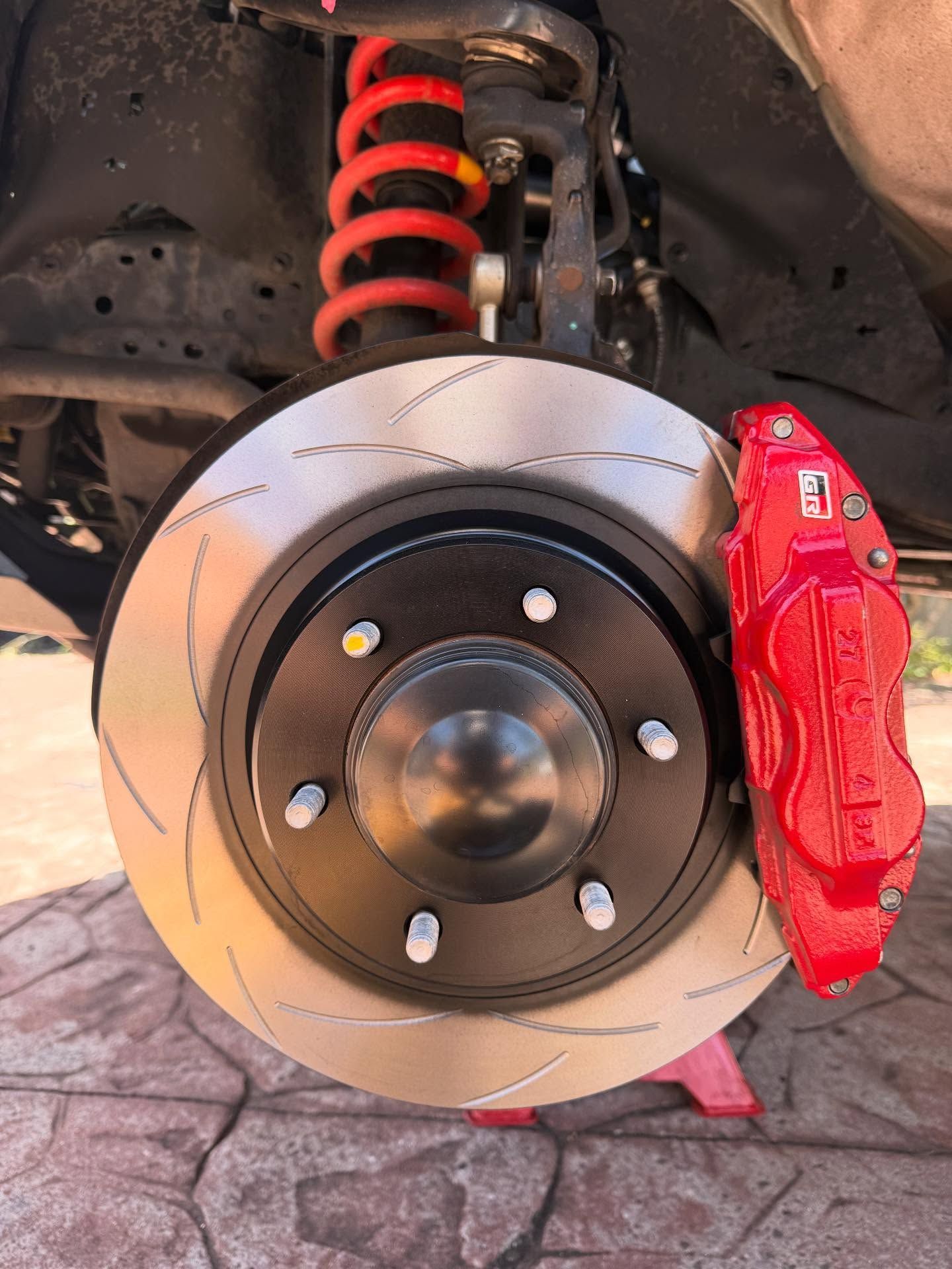 Red Brake Caliper and Slotted Rotor on a Vehicle's Front Wheel — Amrix Automotive In Sefton, NSW