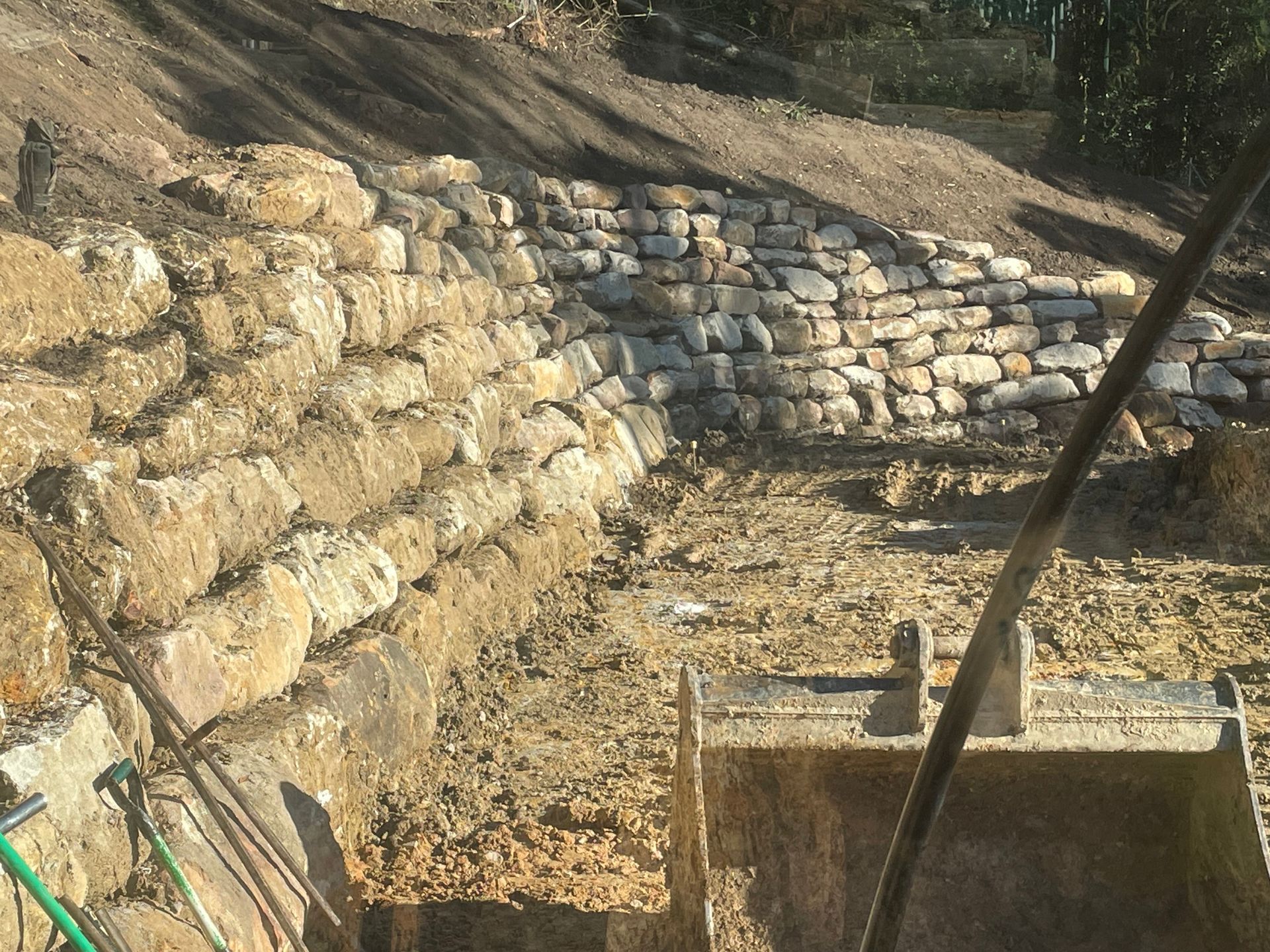 Stone retaining walls under construction on a hillside.