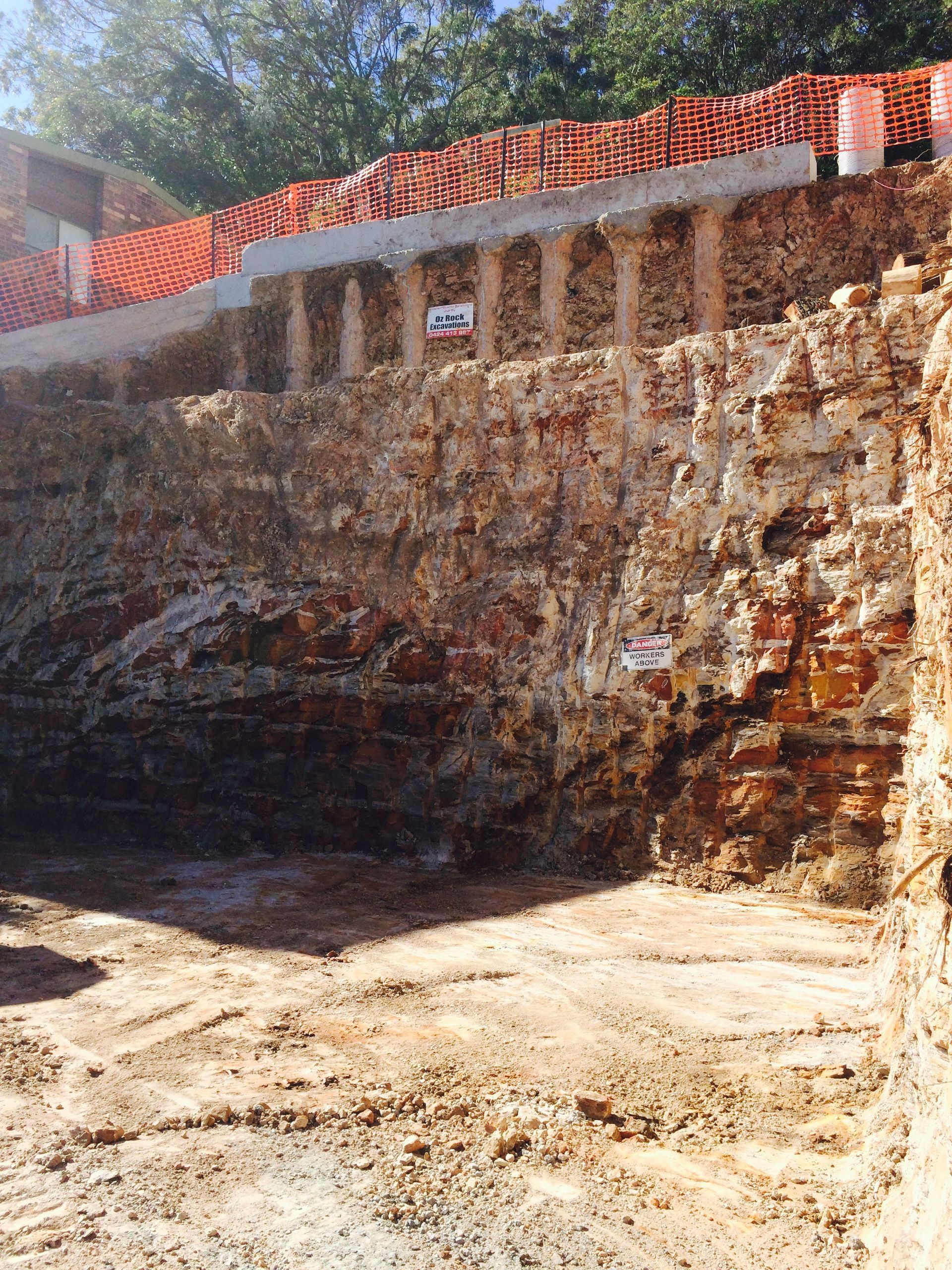 Excavated construction site with exposed brick walls, columns, and a row of red bricks at the top.