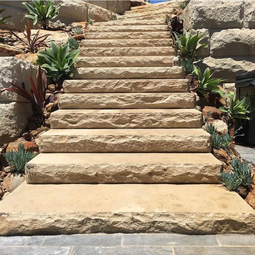 Stone steps leading uphill, surrounded by plants and stone retaining walls.