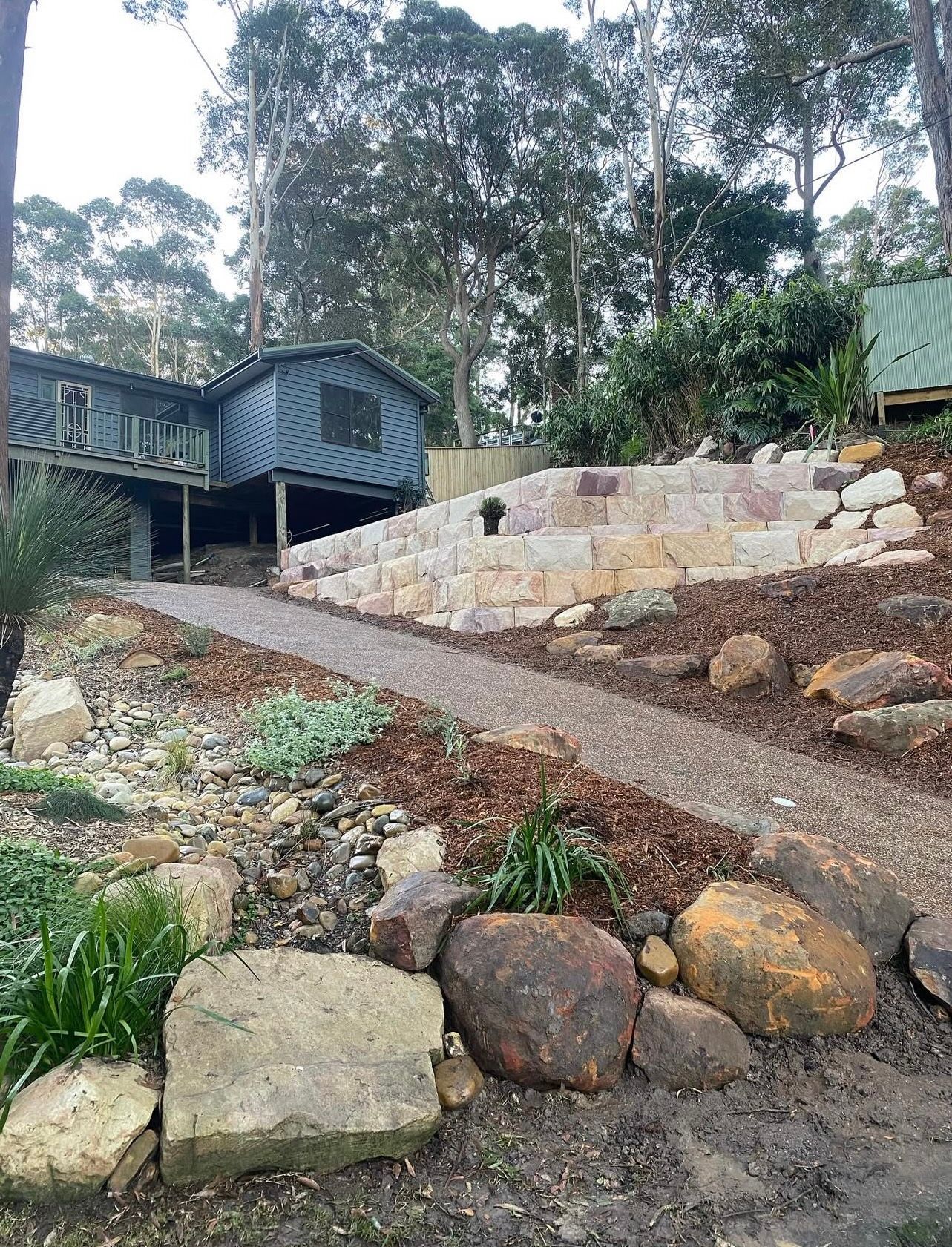 Pathway leading to a rustic cabin built on a hill with stone retaining walls.