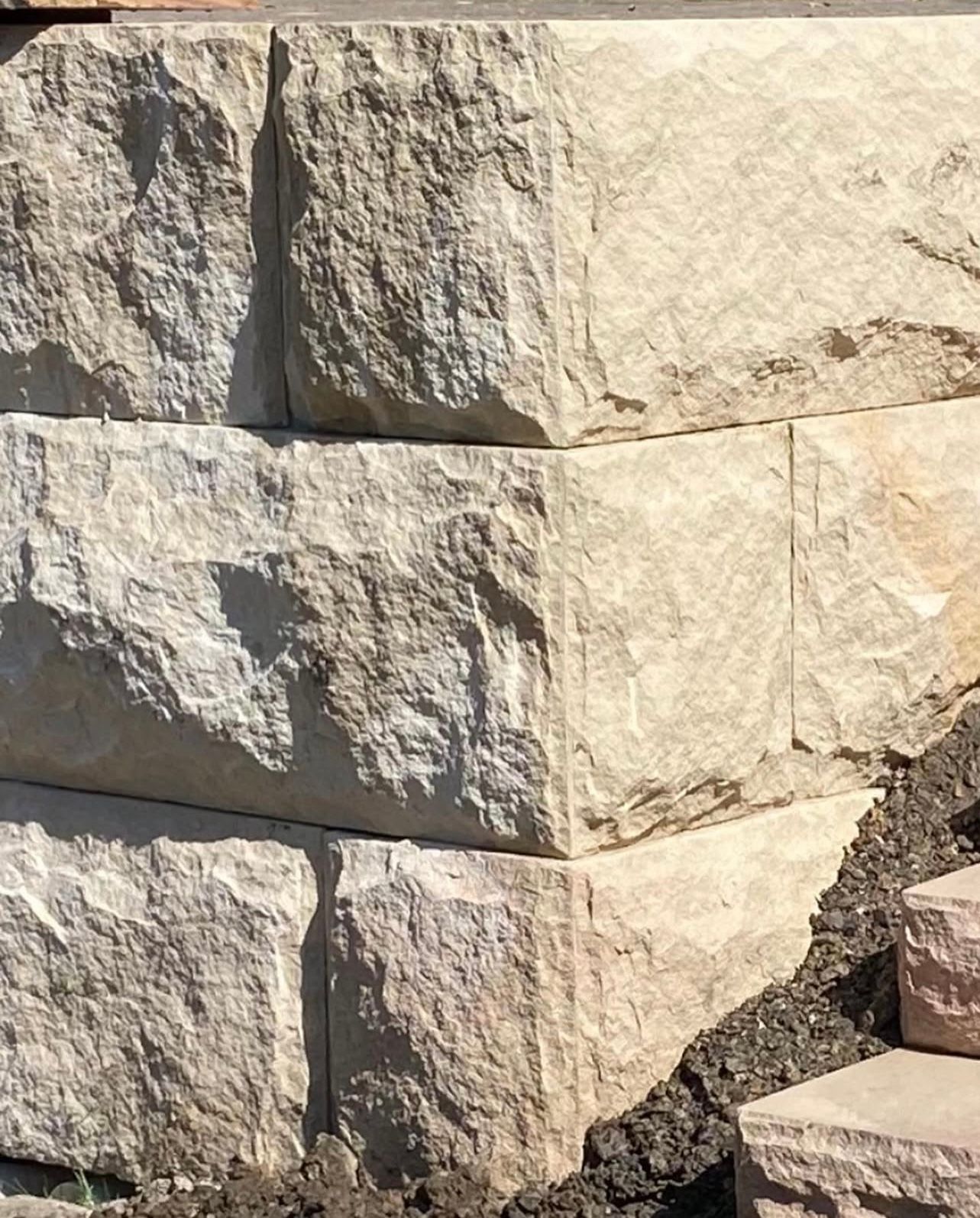 Stone retaining wall with soil and steps; light beige color.