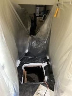 Plastic sheeting-lined hallway with a small chair and a hanging tool or light in the center