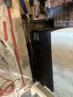 Black electrical panel in a utility area with exposed wiring and insulation