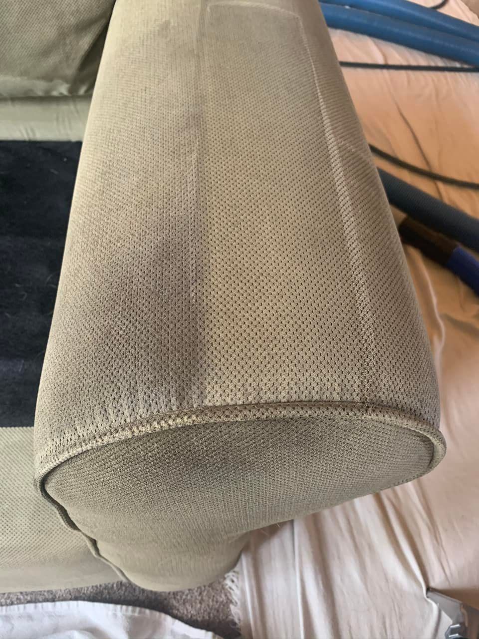Close-up of a beige textured upholstered sofa armrest or cushion end.