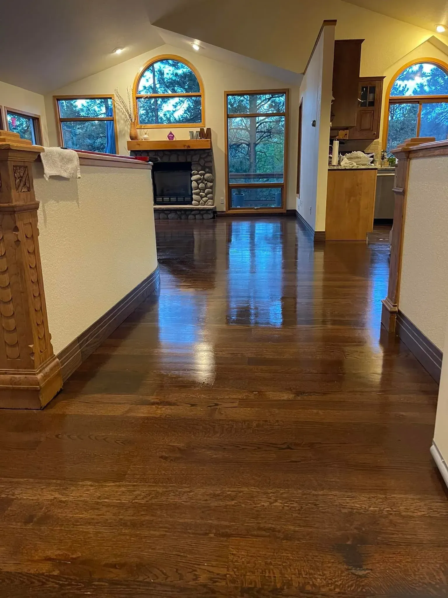 Wooden-floored hallway with arched windows and a fireplace, leading into a warm, spacious home interior