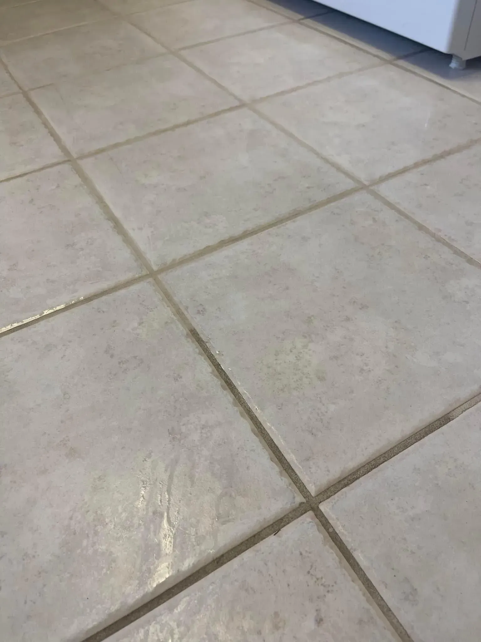 Light beige tiled floor with grout lines, viewed close up indoors.