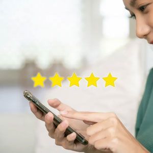 A person holding a smartphone and interacting with a five-star rating icon displayed above the screen.