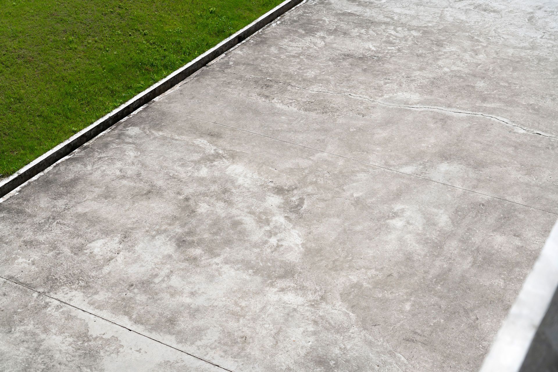 A concrete walkway with grass on the side of it.