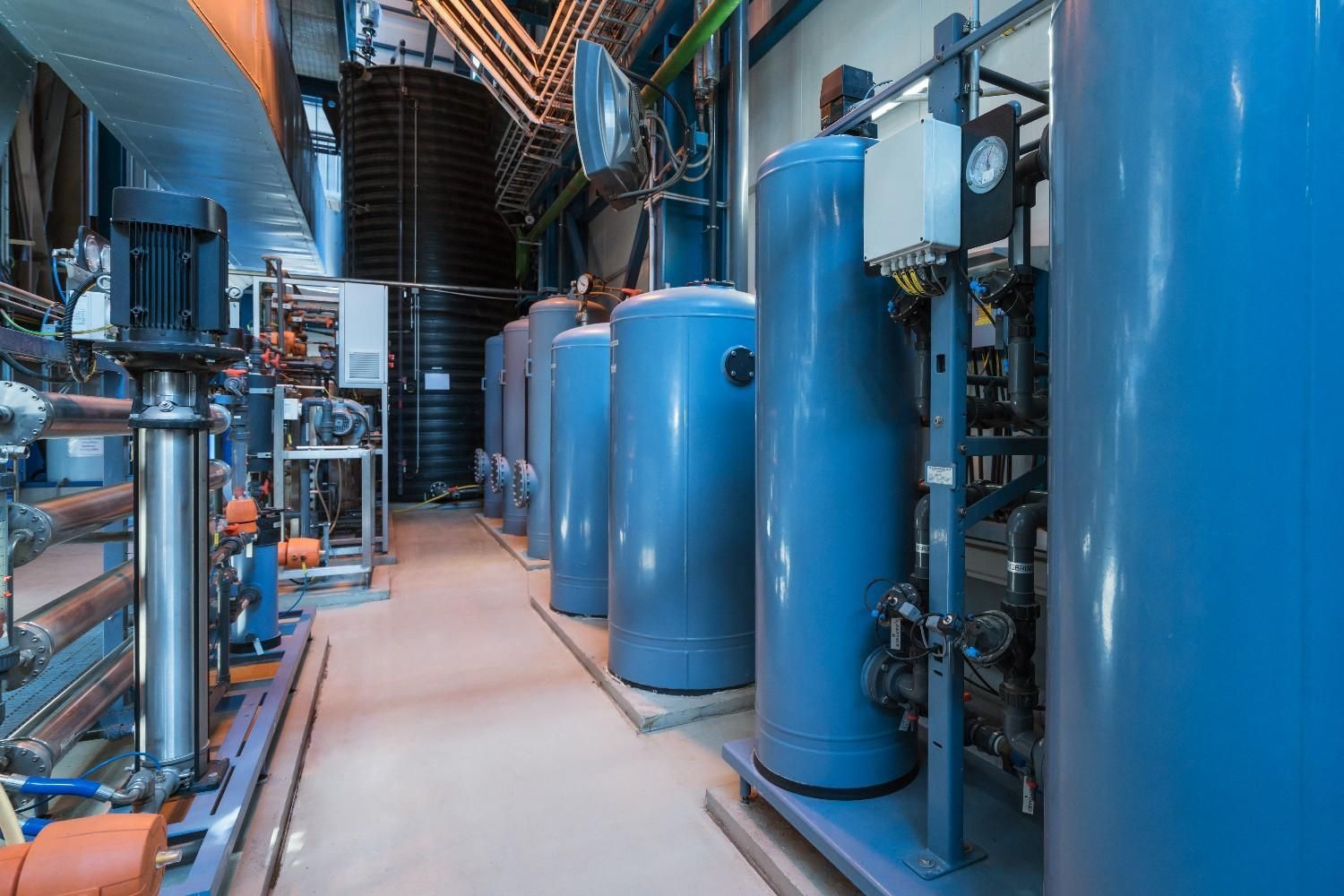 A Row of Blue Tanks Are Lined up In a Factory — B3 Plumbing in Flynn, ACT