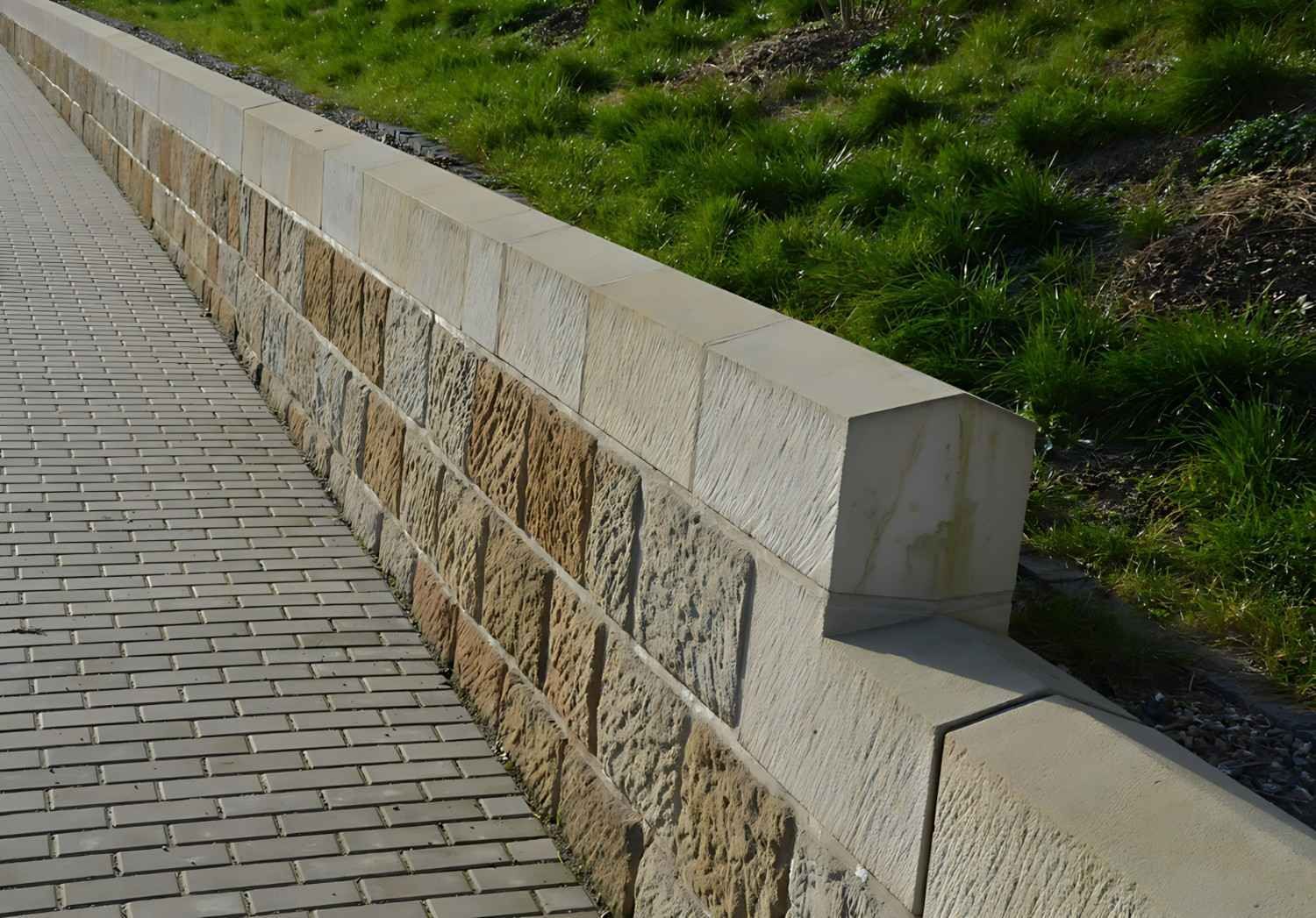A Stone Wall Along a Sidewalk with Grass in The Background — B3 Plumbing in Flynn, ACT