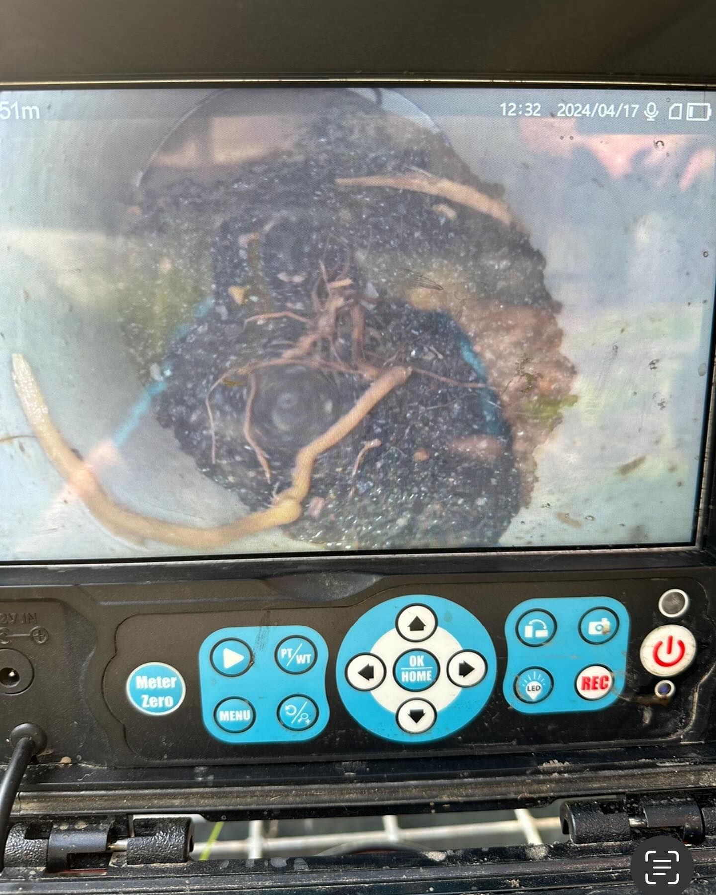 A camera display showing a drain pipe interior filled with debris and roots. The screen's controls are visible below — B3 Plumbing in Flynn, ACT