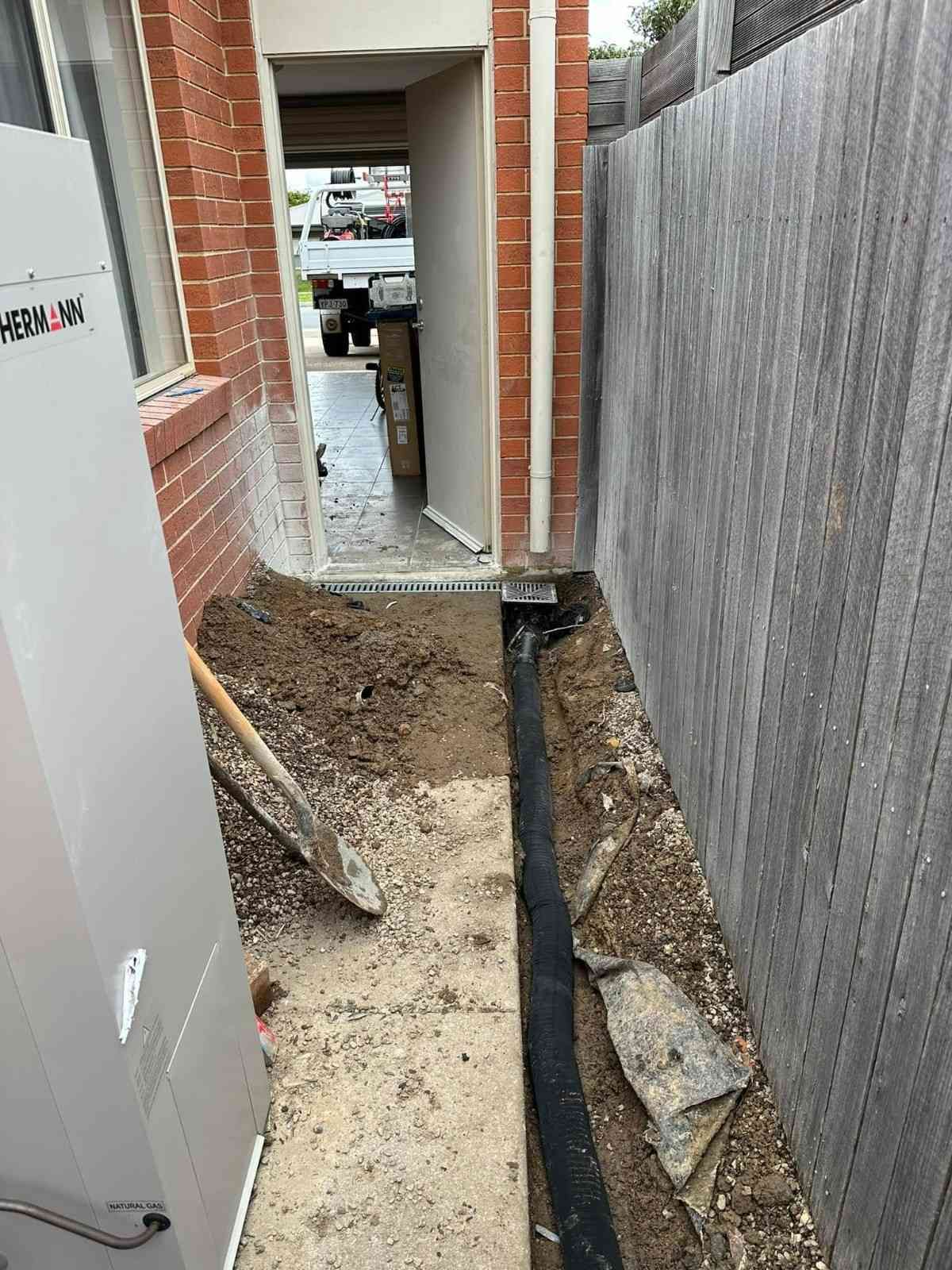 A Drain Pipe Is Being Installed in The Backyard of A House — B3 Plumbing in Flynn, ACT