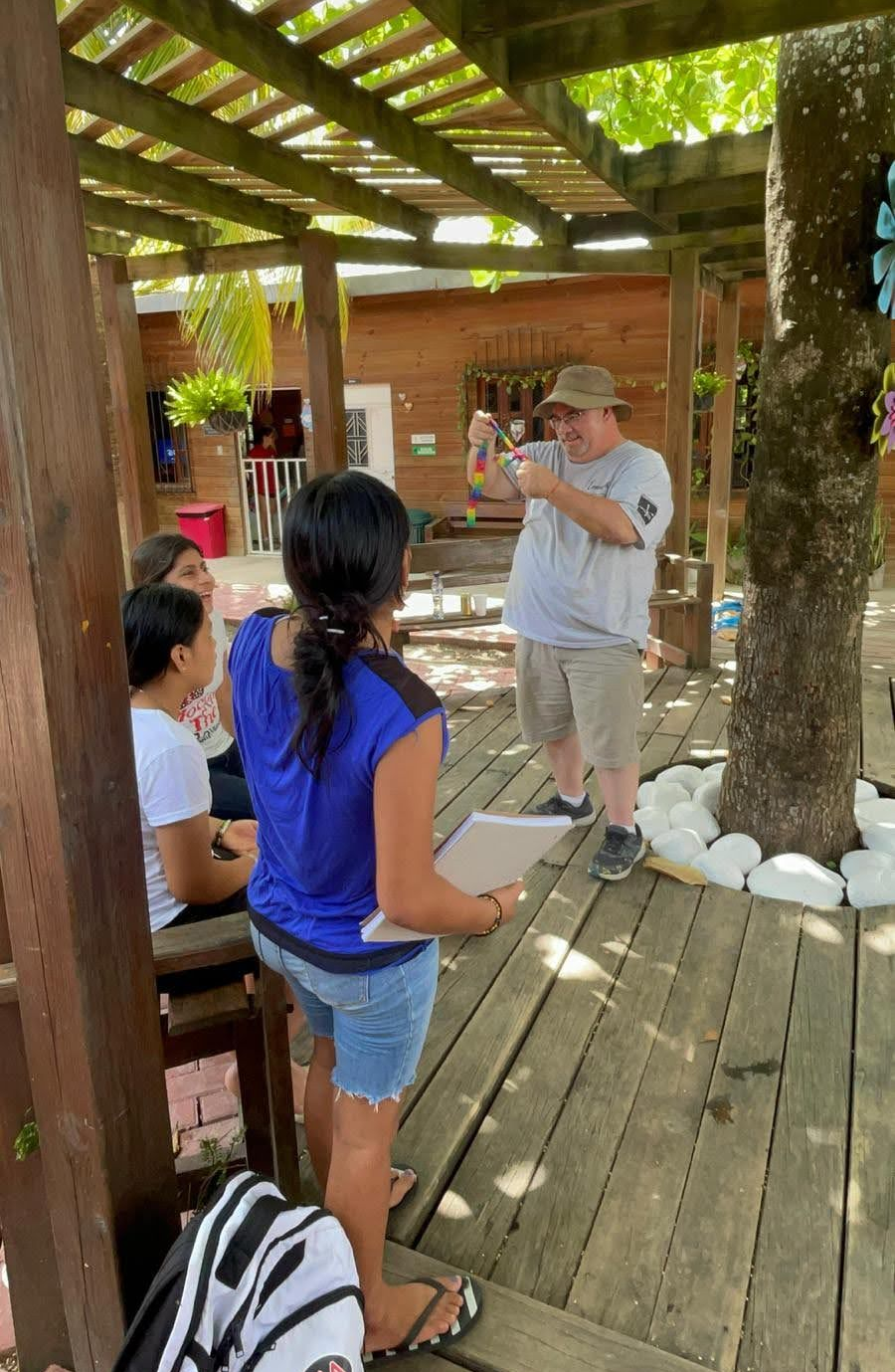 Man in light gray shirt doing magic for girls in Guatemala