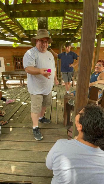 Man in light gray shirt doing magic for girls in Guatemala