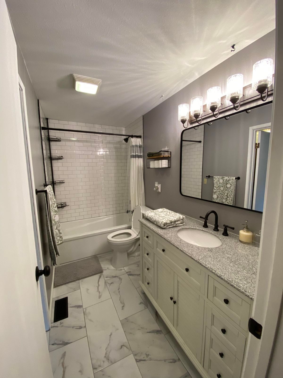 Bathroom with white vanity, gray walls, and marble-look floor tiles. A