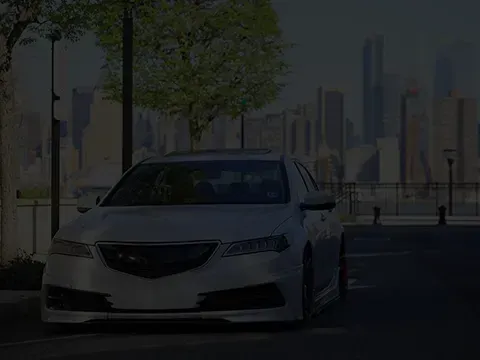 White sedan parked on a street with a city skyline in the background. | Automotive Excellence