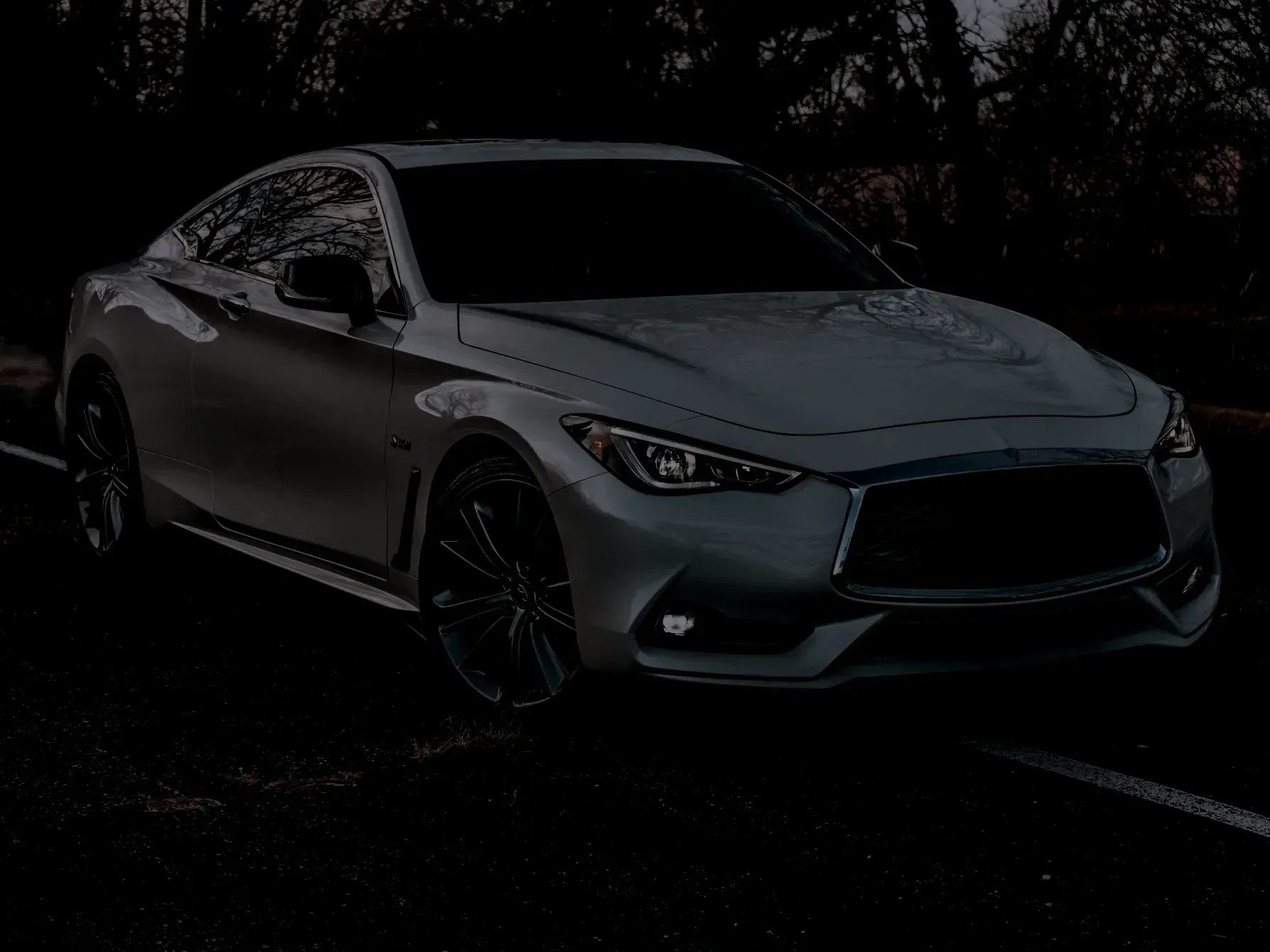 Silver Infiniti Q60 coupe on a road at dusk; dark background. | Automotive Excellence