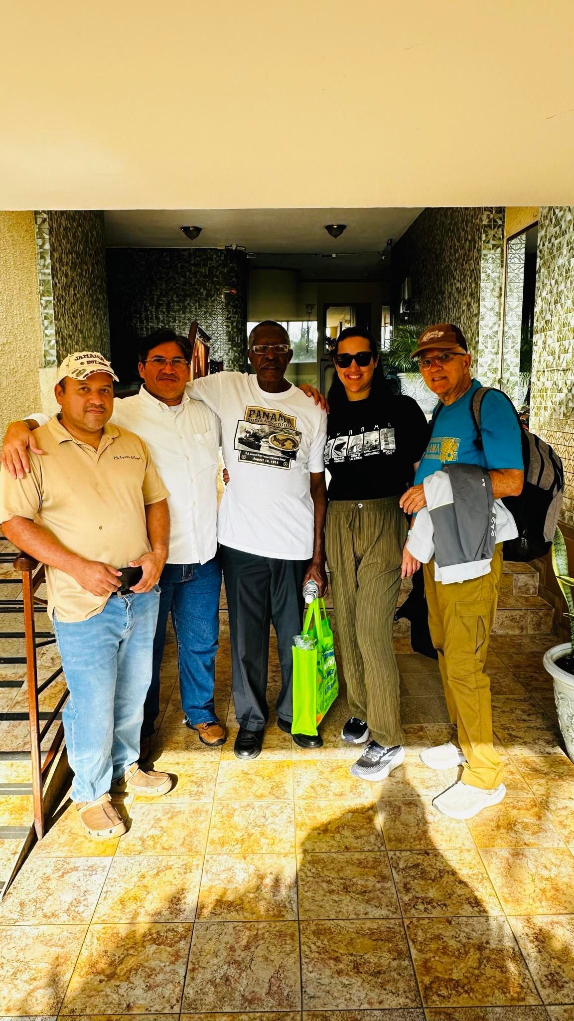 Group of five people posing outdoors in front of a building. They are smiling and looking at the camera.