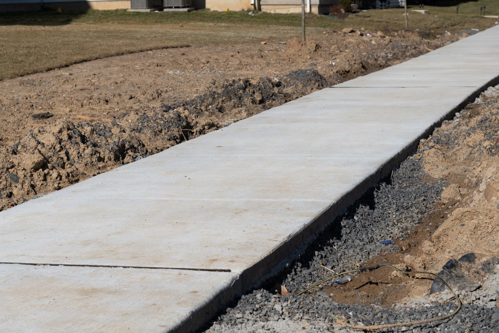 A recently cured concrete sidewalk constructed in front of a house.