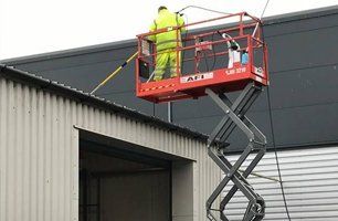 Man pressure cleaning factory roof