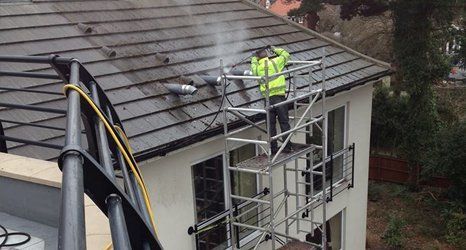 man pressure cleaning a roof