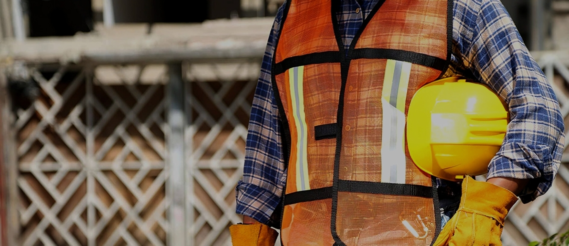 Un trabajador de la construcción sostiene un casco y guantes.