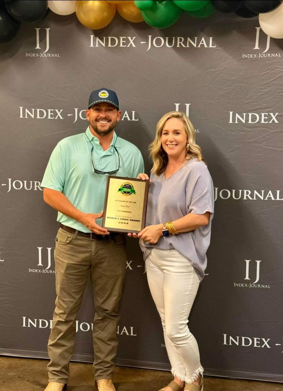 A man and a woman are standing next to each other holding a plaque.