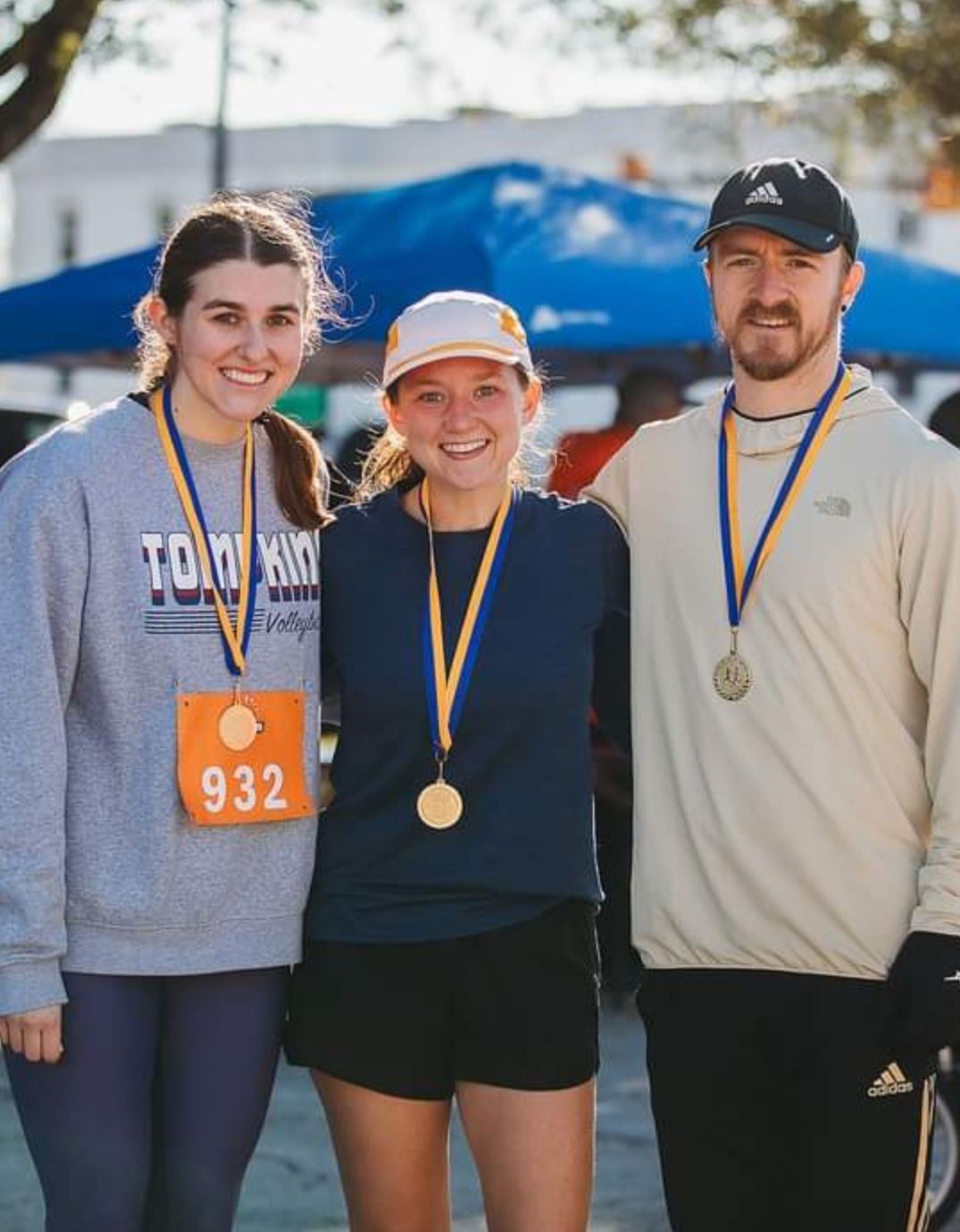 A man and two women are posing for a picture with medals around their necks.
