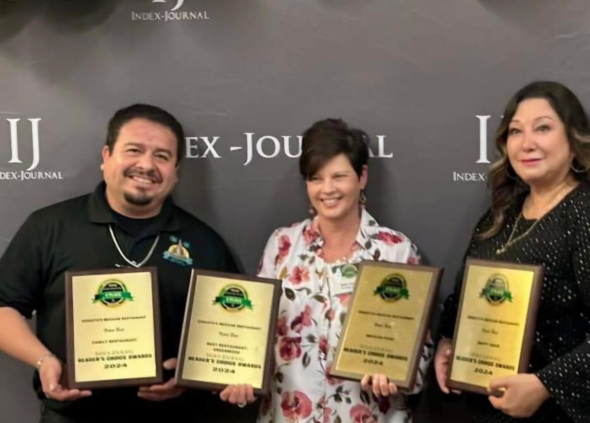 A group of people holding plaques in front of a wall that says ex-jou