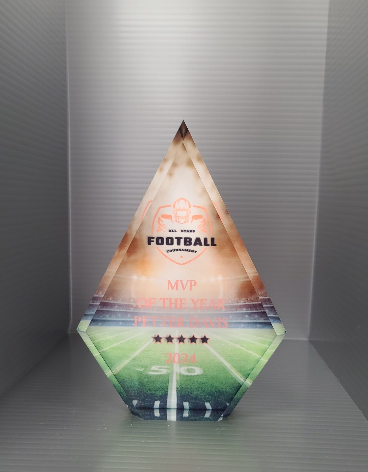 A diamond shaped football trophy is sitting on a table.