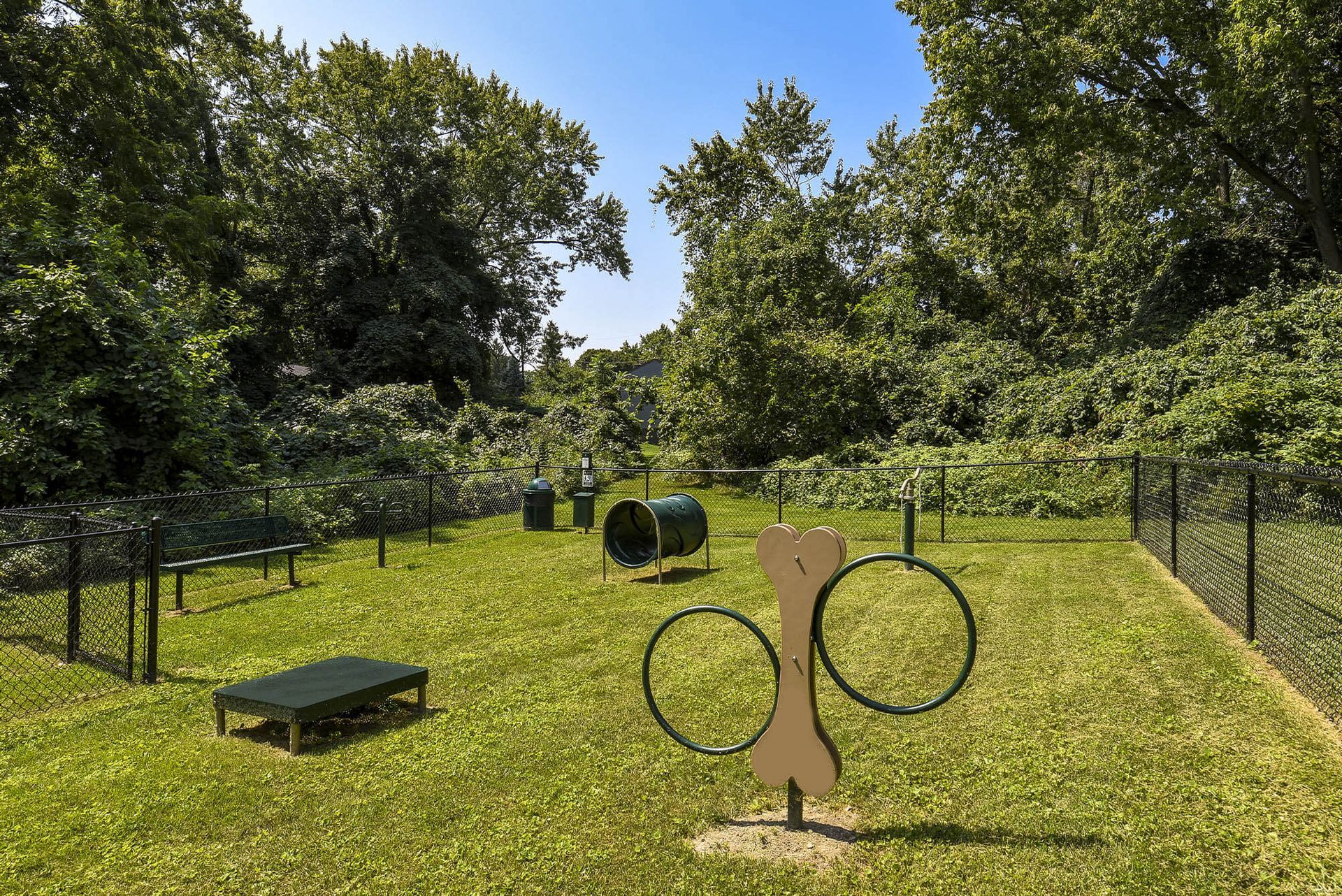 Fenced grassy community park with playground equipment, benches, and trees at the Reserves at Arlington in Columbus, OH.