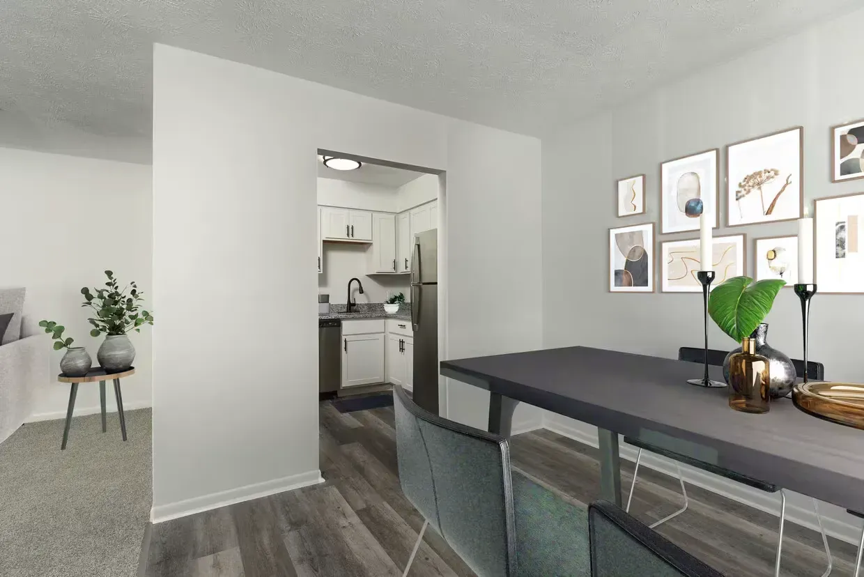 Dining area with a dark table and chairs, wall art, and a kitchen opening at the Reserves at Arlington in Columbus, OH.